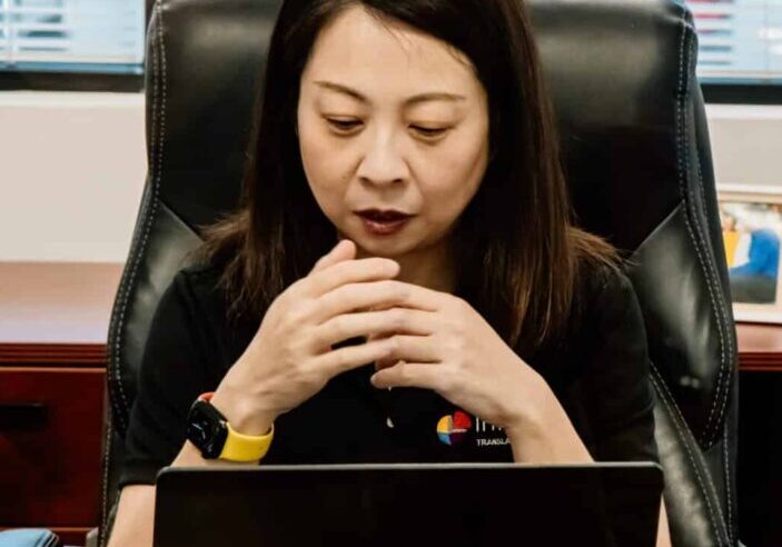 Interpro Chinese team member sitting at desk coordinating professional translation services from laptop.
