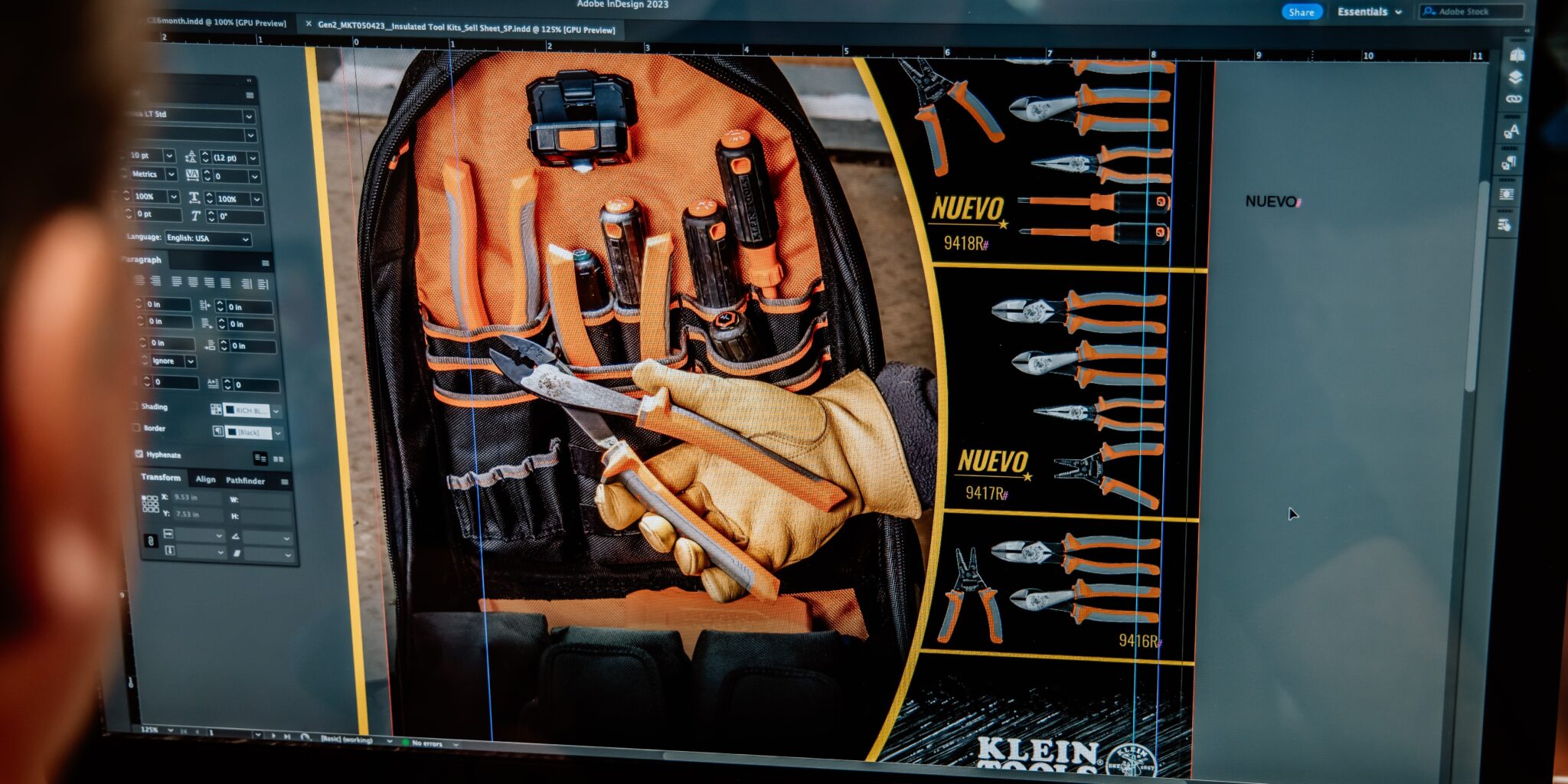 Two team members reviewing a multilingual design project on a desktop screen in an office setting