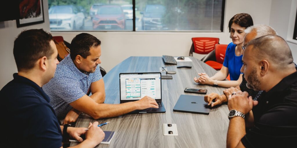 Business team reviewing translation strategy on a laptop during a meeting about global document compliance and localization best practices.