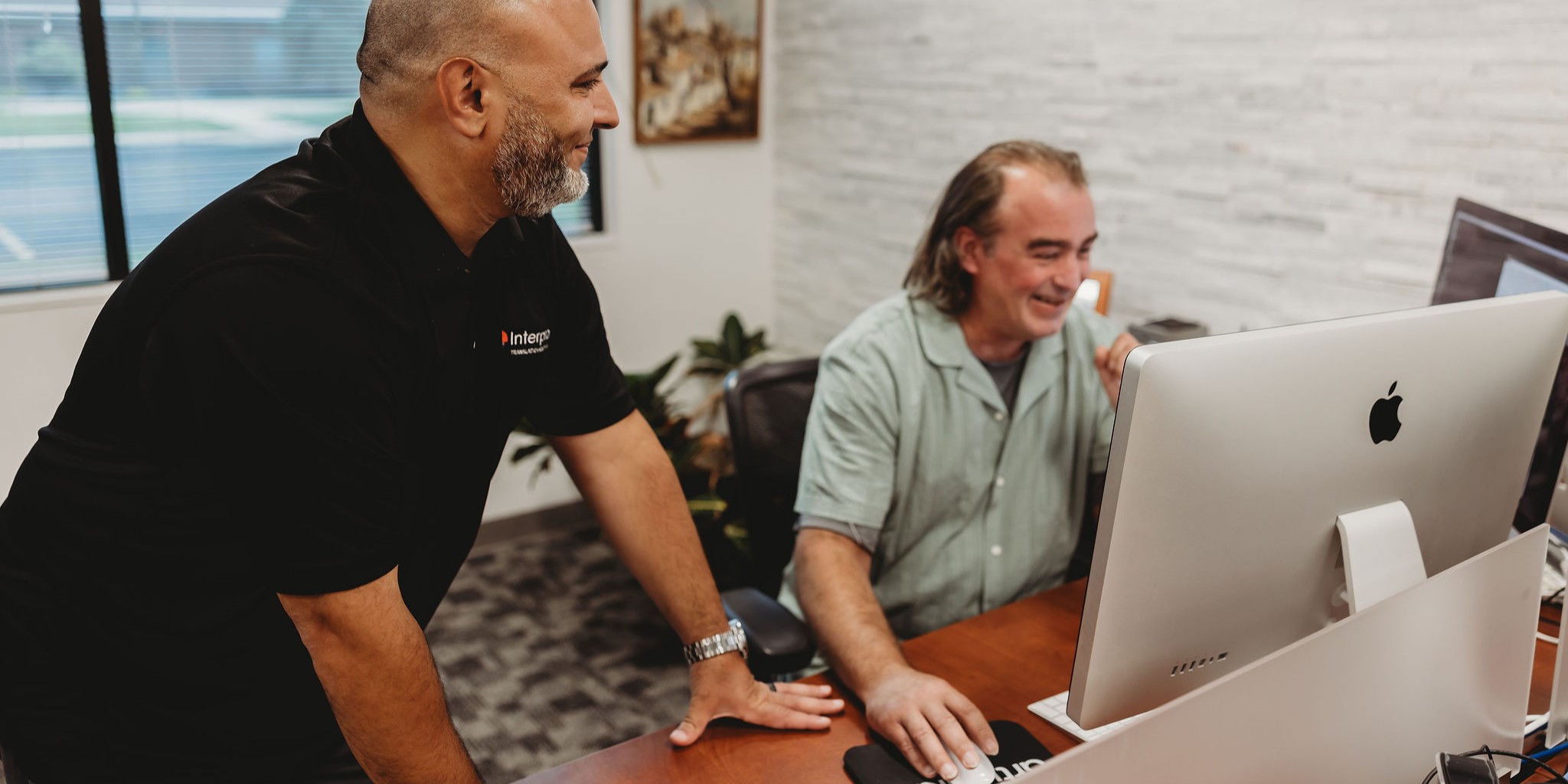 Two translation professionals collaborating at a computer in the Interpro office
