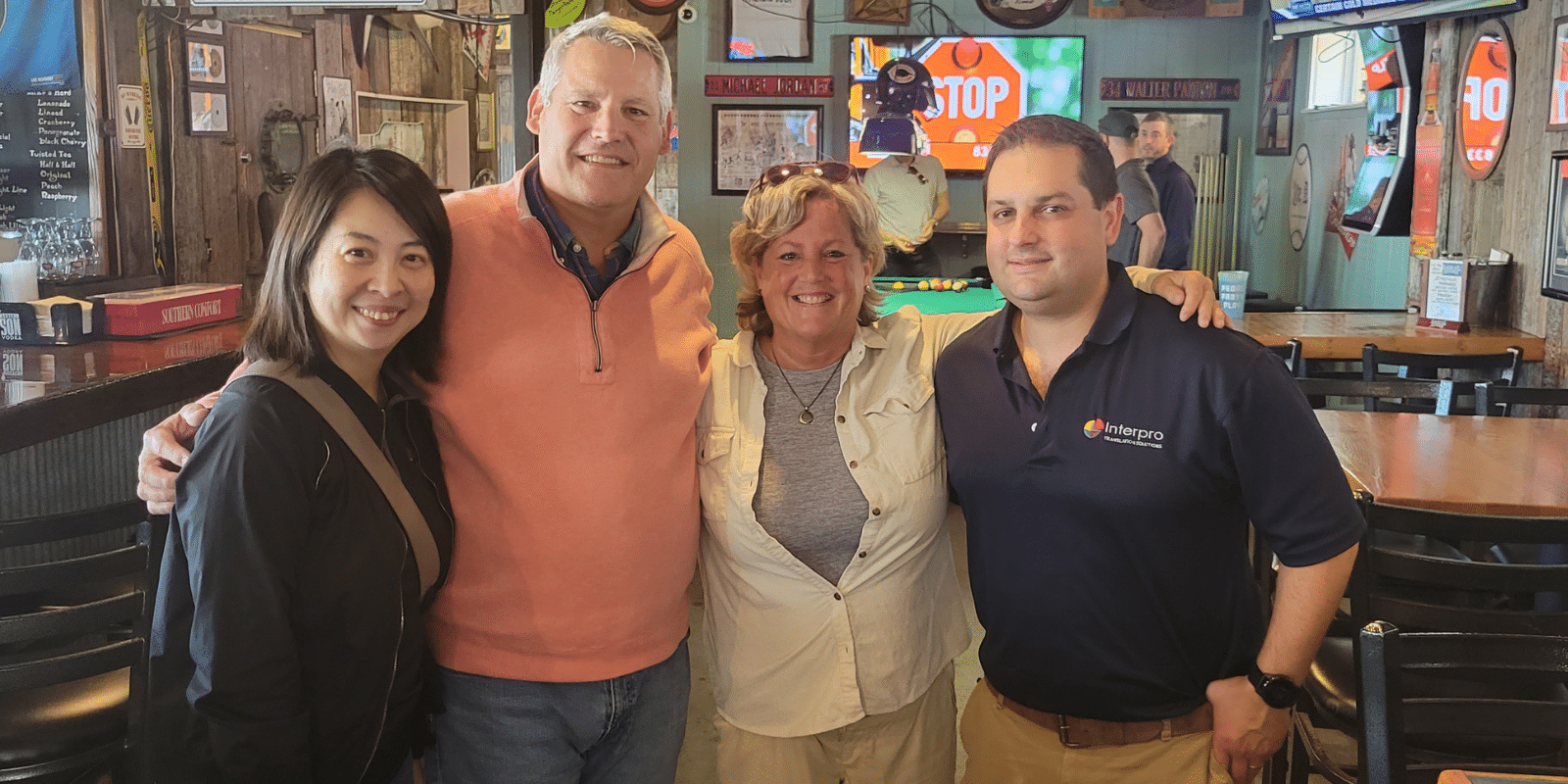 Four people smiling in a bar, two are Interpro employees, two are Armstrong International employees.